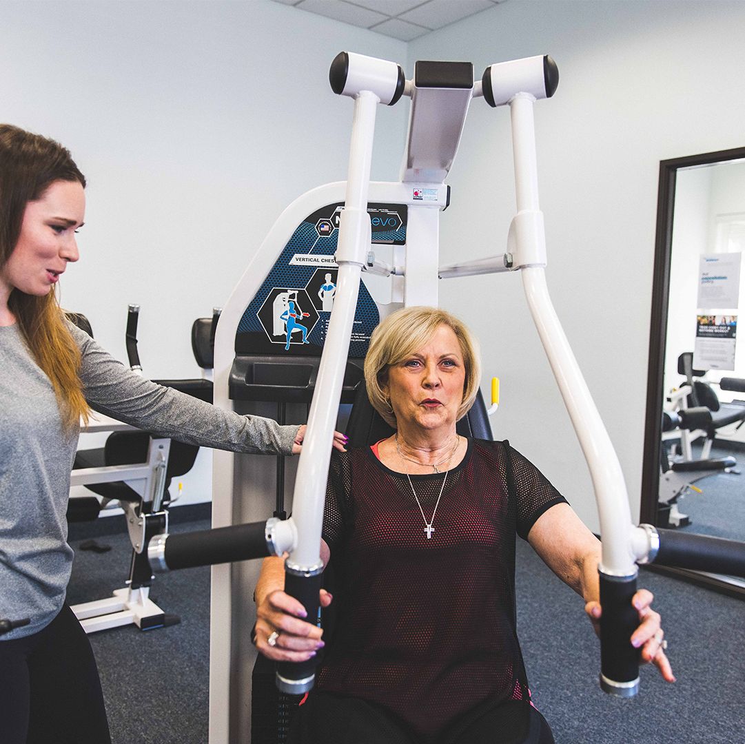 A woman using the chest press machine at The Perfect Workout