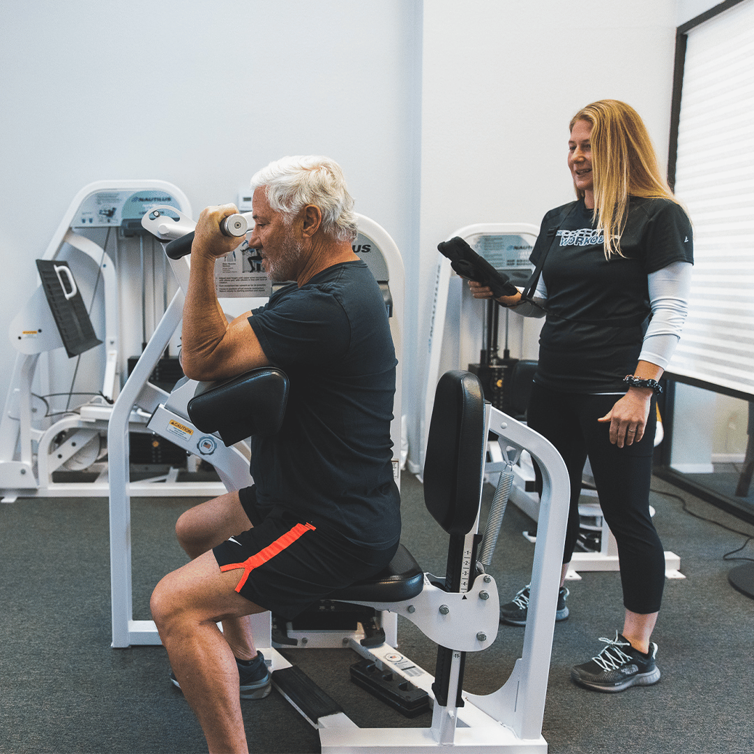 An older man working out on the preacher curl machine at The Perfect Workout