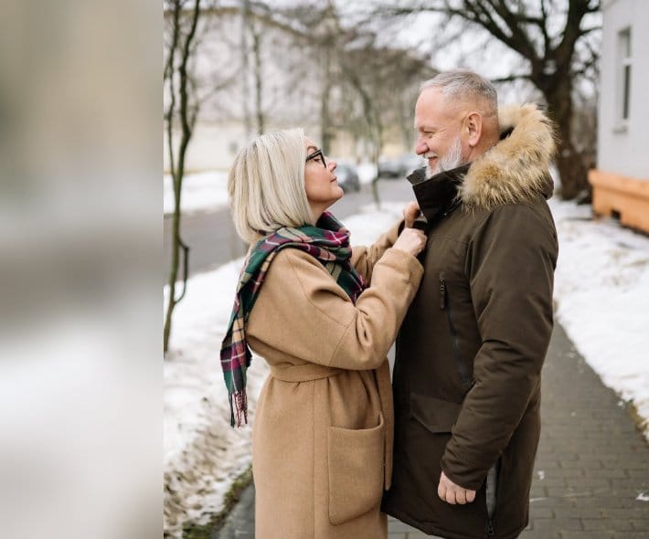 Affectionate senior couple in winter attire, sharing a moment of connection and joy outdoors.