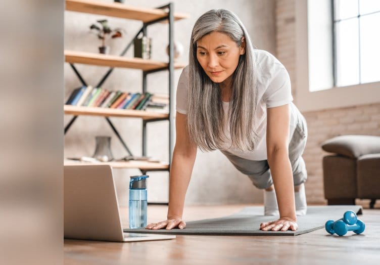 woman performing a plank exercise at home while following an online fitness session, illustrating dedication to health