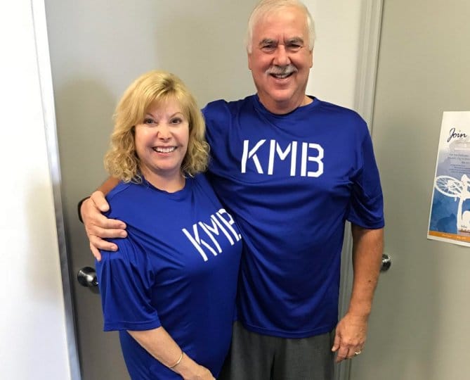 Cheerful couple in matching blue shirts, celebrating their wellness achievements.