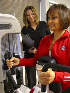 Female client working with a personal trainer on an exercise machine