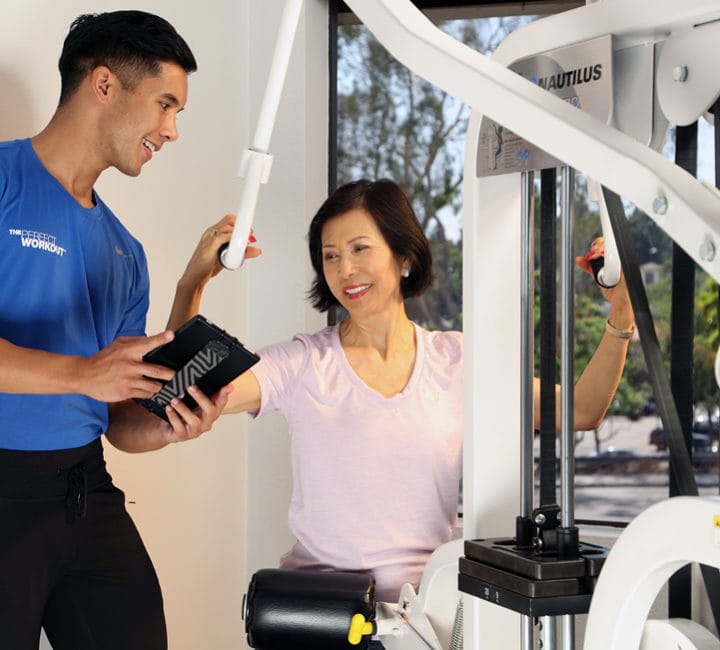Woman working out on machine with male trainer