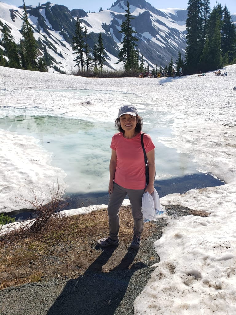woman standing on a mountainside with snowy mountains in the background