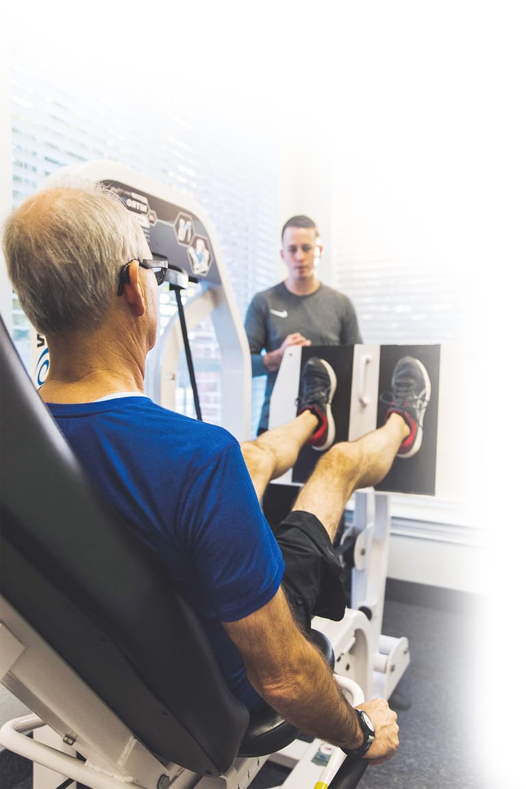 male client doing a leg press with a personal trainer