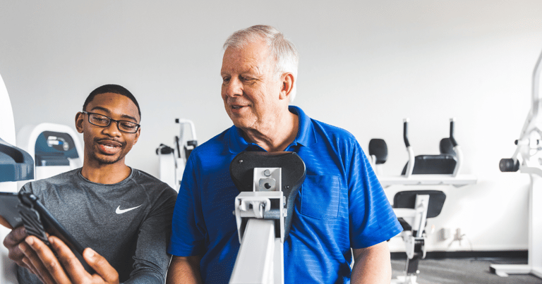 trainer showing a male client his progress on the compound row