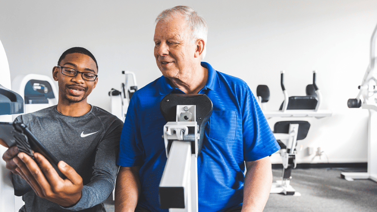 A trainer showing a man the progress he's made with strength training at The Perfect Workout