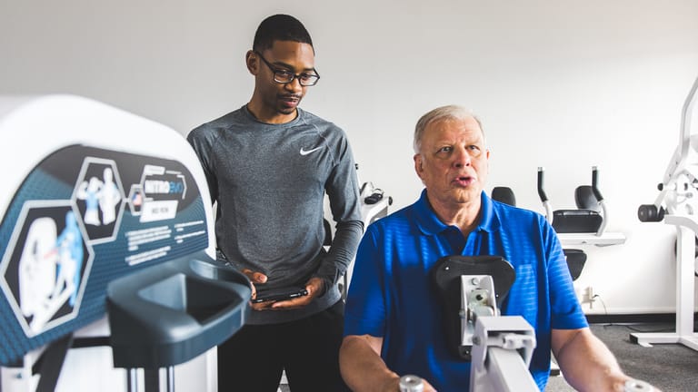 Image of a male trainer directing a Member on the Compound Row