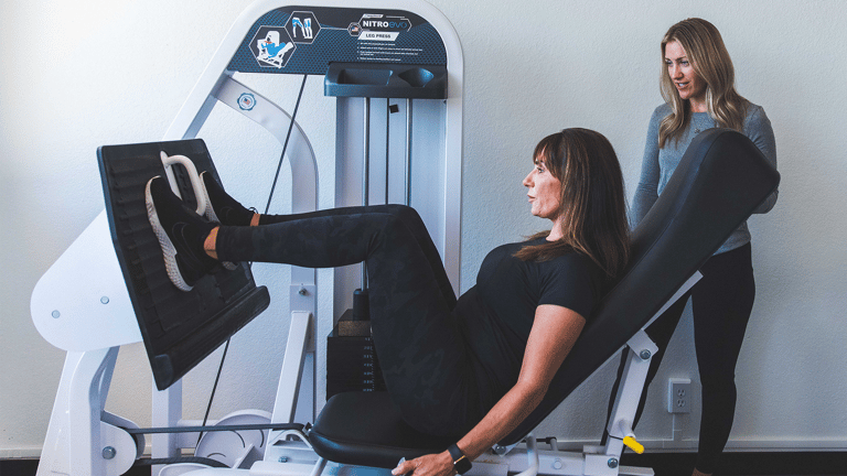 Image of a training working with a female member on the leg press