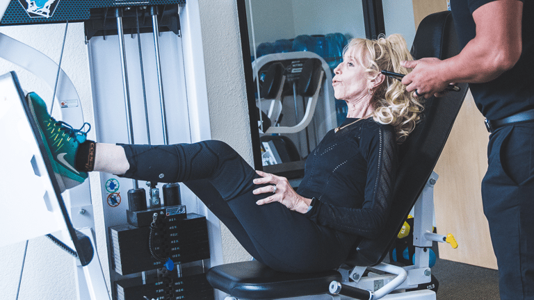 image of a female doing the leg press with a knee brace on