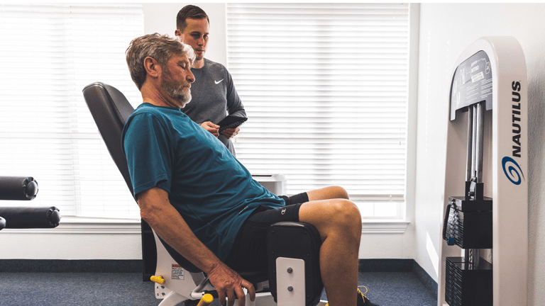 Image of a trainer teaching a man to us the abduction machine