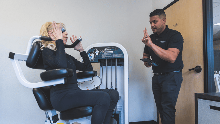 Image of a San Francisco Bay Area trainer helping a member of The Perfect Workout on the ab machine