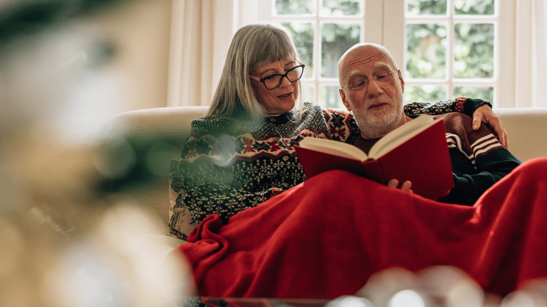 A couple relaxing on the couch enjoying a book during the holidays