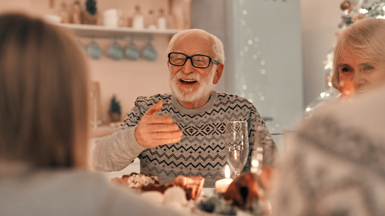 A family laughing together around the dinner table during the holidays