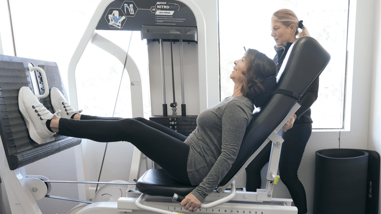 A woman being coached on the leg press machine