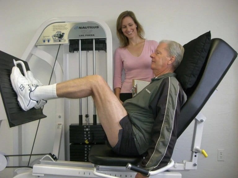 male client with female trainer doing a leg press on a machine