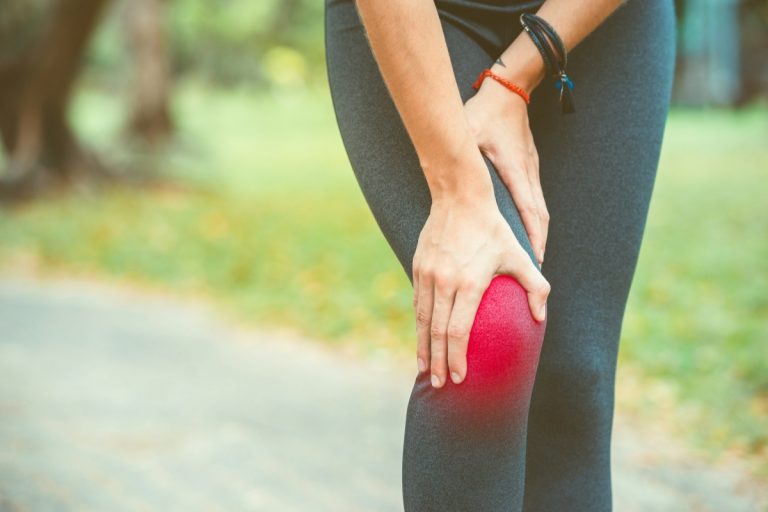woman with her hand on her knee hurting from inflammation