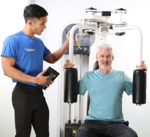 man on chest fly machine with male trainer
