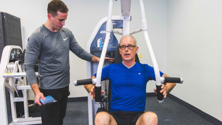 Trainer coaching male member on the chest press machine