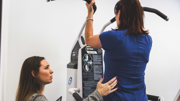 Female Trainer coaching a Female member on the Gravitron machine