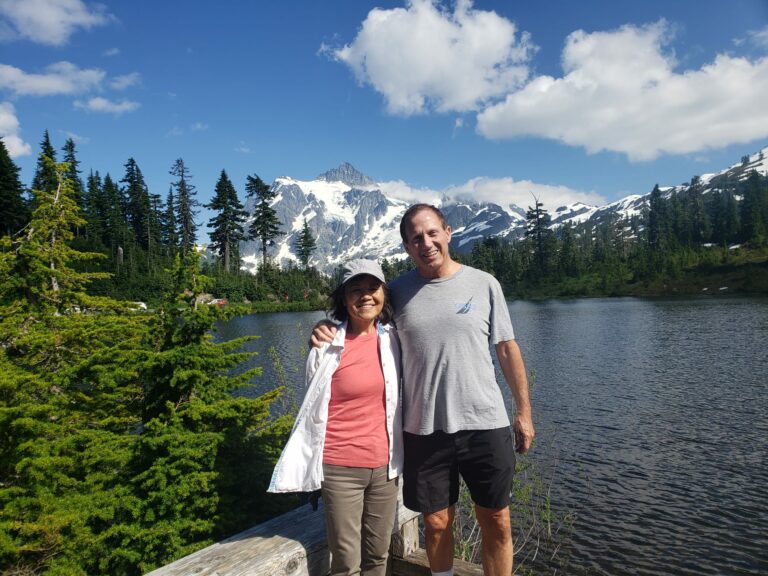 husband and wife stopping for a photo in front of mountains