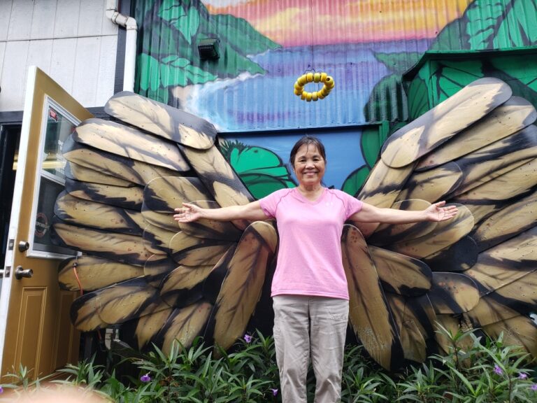 woman standing in front of a mural of angel wings with a halo above her