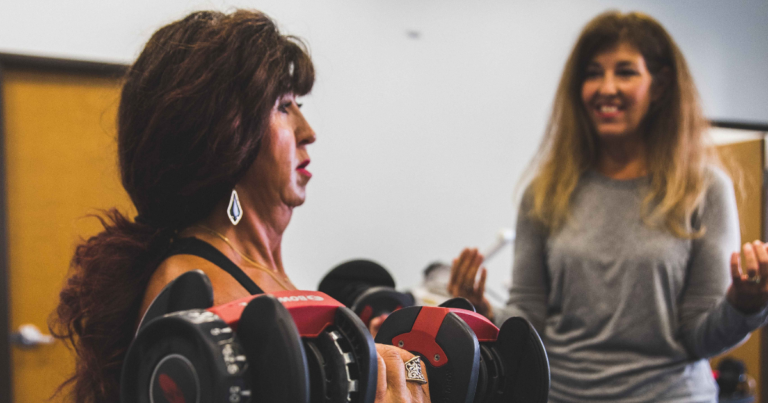 Trainer coaching member on how to do bicep curls