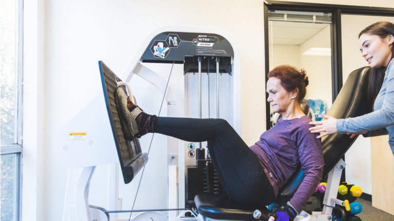 Image of Valerie coaching a member on the leg press