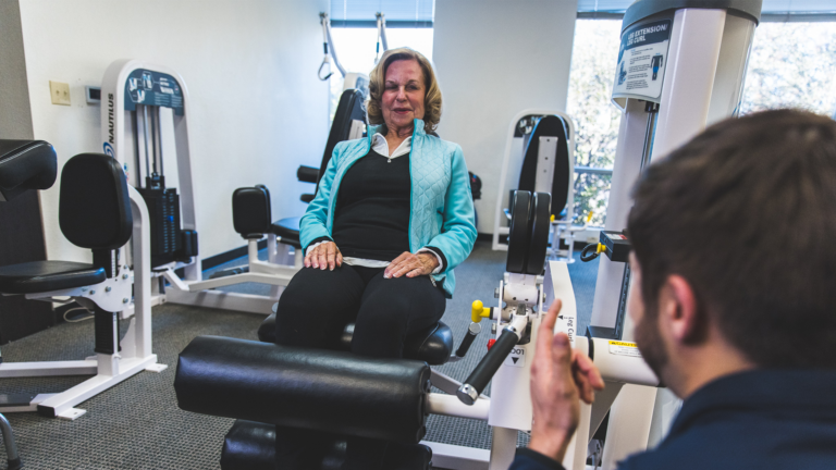 Image of a female being coached by a trainer on the leg extension machine