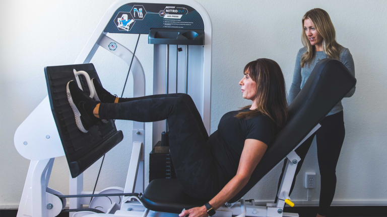 Image of a training working with a female member on the leg press