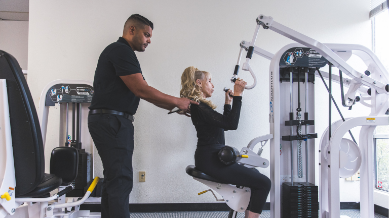 Image of a The Perfect Workout manager training a member on the lat pulldown machine