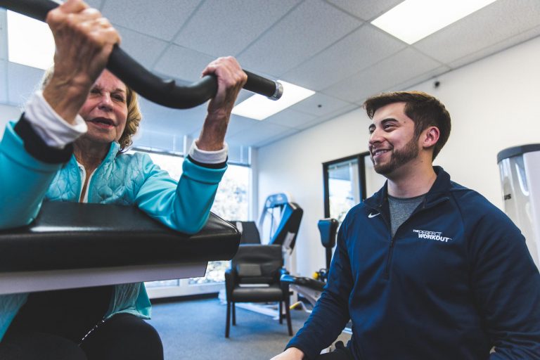 The Perfect Workout Trainer guiding a woman through a preacher curl exercise