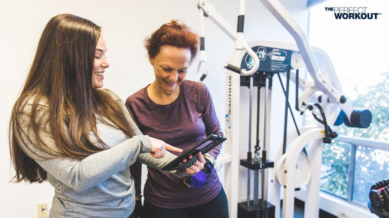Image of a trainer at The Perfect Workout showing a member their incredible results