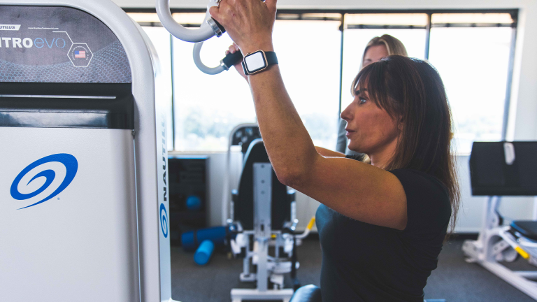 A female member from The Perfect Workout exercising on the Lat Pulldown