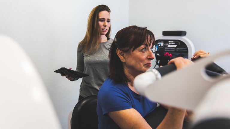 A trainer guiding a member through the preacher curl exercise at The Perfect Workout
