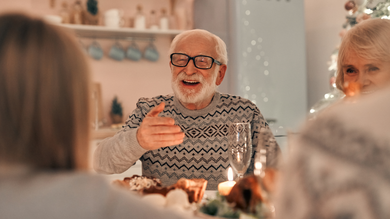 A family laughing together around the dinner table during the holidays