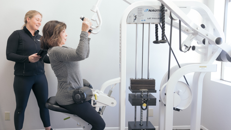 A woman works out on the Lat Pulldown machine at The Perfect Workout