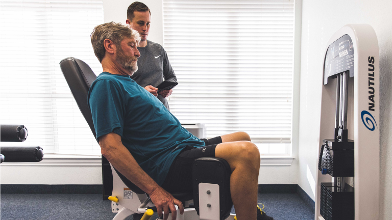 A trainer at The Perfect Workout coaches a man through abduction exercises