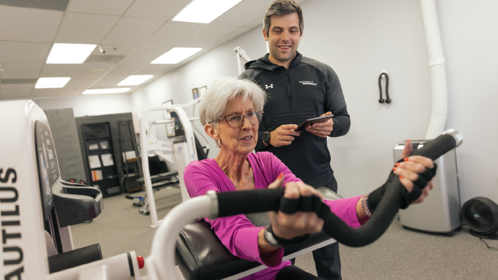 A trainer helping a woman do bicep curls