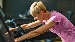 A woman with high cortisol levels is exhausted from overworking herself in the gym